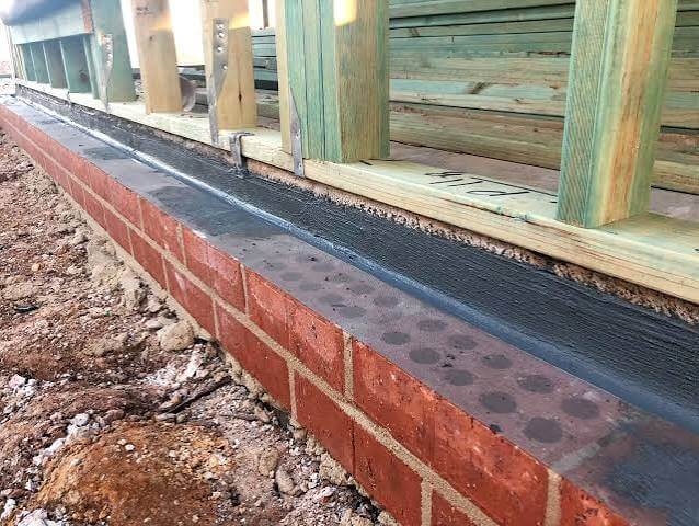 Metal termite shield installed between brick foundation and timber frame during construction